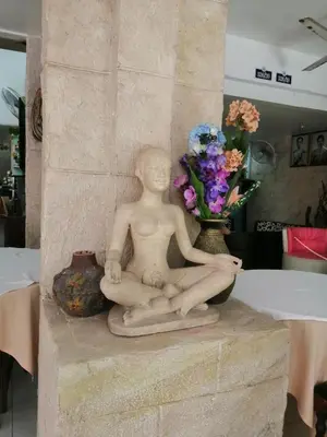 a statue of a man sitting next to a vase of flowers at Da Mario Hotel & Restaurant in Karon Beach