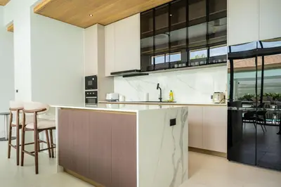 an open kitchen with a counter and stools at Mouana Breeze Mai Khao 4-bedroom Pool Villa 9922 in Mai Khao Beach