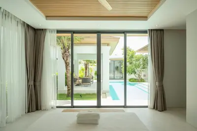 an open living room with sliding glass doors to a pool at Mouana Breeze Mai Khao 4-bedroom Pool Villa 9922 in Mai Khao Beach
