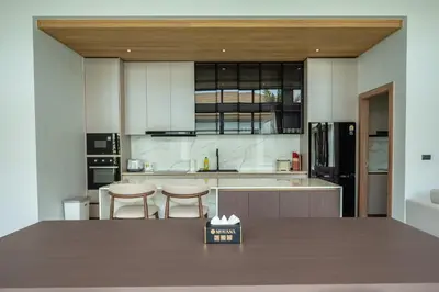 a kitchen with a table and two stools in it at Mouana Breeze Mai Khao 4-bedroom Pool Villa 9921 in Mai Khao Beach