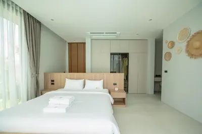 a bedroom with a large bed with white sheets at Mouana Breeze Mai Khao 4-bedroom Pool Villa 9921 in Mai Khao Beach