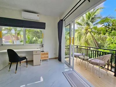 a room with a balcony with a desk and chairs at The Green View Pool Villa in Kamala Beach