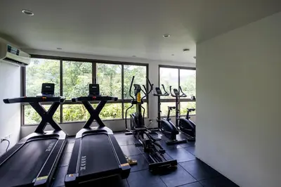 a gym with several treadmills in a room with windows at Kamala Modern 2 bedroom Apartment in Kamala Beach