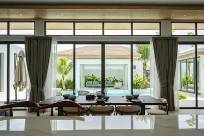 a dining room with a table and chairs and large windows at Mouana Breeze Mai Khao 4-bedroom Pool Villa 9920 in Mai Khao Beach