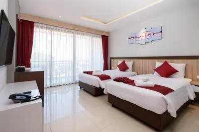 a hotel room with two beds and a television at Paripas Patong Resort in Patong Beach