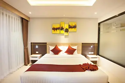 a bedroom with a large white bed with red pillows at Paripas Patong Resort in Patong Beach