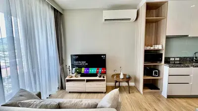 a living room with a couch and a flat screen tv at Apartment Diamond Resort BangTao in Bang Tao Beach