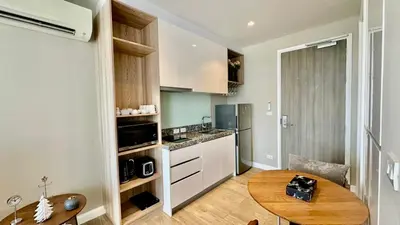 a small kitchen with a wooden table and a dining room at Apartment Diamond Resort BangTao in Bang Tao Beach