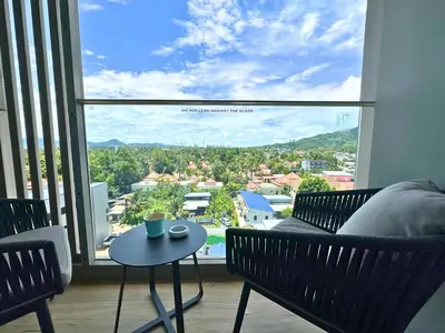 a room with a couch and a table and a large window at Apartment Diamond Resort BangTao in Bang Tao Beach