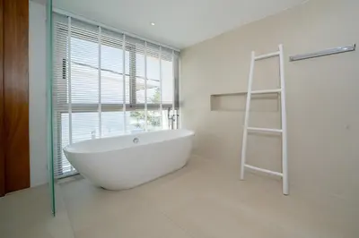 a bathroom with a white bath tub and a window at The Trinity new modern 5BR villa with 20M Pool in Thalang