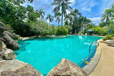 a swimming pool with blue water and palm trees at Laguna Lakeshore Villas Residence - Spacious Townhouse with Tropical Pool Access in Bang Tao Beach