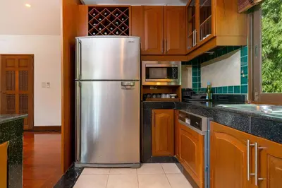a stainless steel refrigerator in a kitchen with wooden cabinets at Laguna Lakeshore Villas Residence - Spacious Townhouse with Tropical Pool Access in Bang Tao Beach