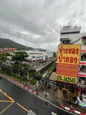 a city street with a large yellow sign on a building at SK Residence And Restaurant Patong in Patong Beach