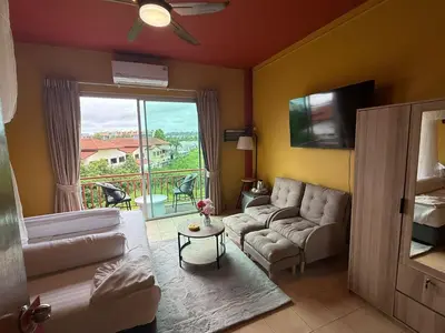 a living room with a couch and a tv at Alura Guesthouse in Kata Beach