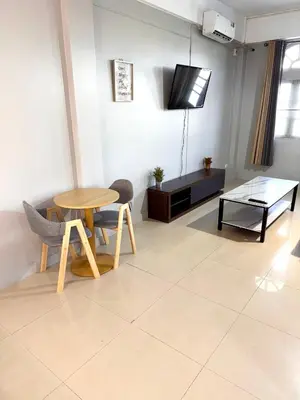 a living room with a table and a tv at Green Terrace Residence Phuket in Kathu