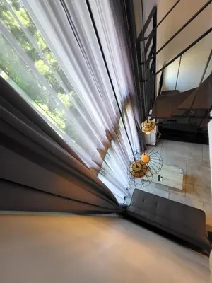 a large window in a living room with a couch at Modern Naiharn Beach Duplex Apartment in Rawai Beach