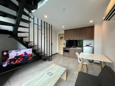 a living room with a tv and a table and a kitchen at Modern Naiharn Beach Duplex Apartment in Rawai Beach