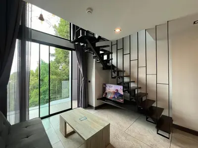 a living room with a spiral staircase and a table at Modern Naiharn Beach Duplex Apartment in Rawai Beach