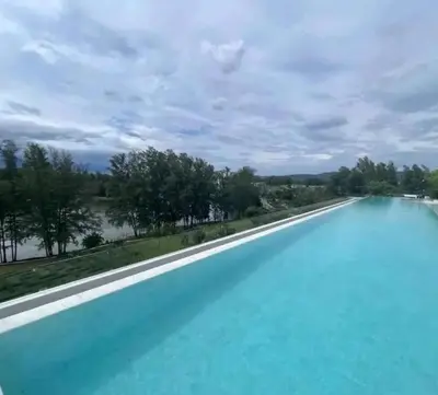a large swimming pool with blue water next to a river at Аппартаменты Sky Park Laguna Phuket in Bang Tao Beach