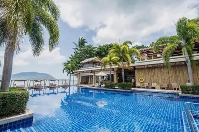 a swimming pool with palm trees and a building at NEW Malee Resort Studio 858 in Rawai Beach