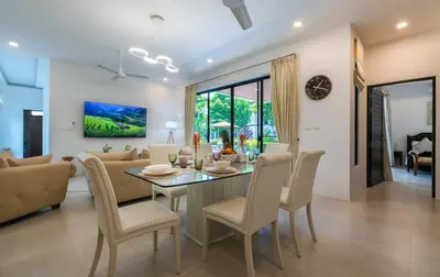 a dining room and living room with a table and chairs at V187 Walkable to Beach Very modern Jacuzzi pool in Rawai Beach