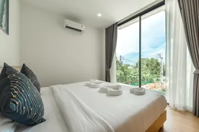 a bedroom with a white bed with a large window at V190 Tropical Oasis 3BR Villa with Pool & Bathtub in Rawai Beach
