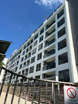 a tall white building with a sign in front of it at Fantasea Condominium Kamala in Kamala Beach