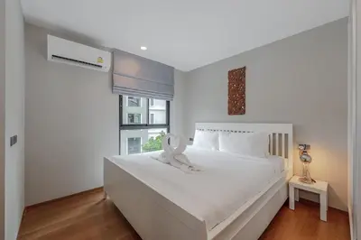 a white bedroom with a large white bed with a ribbon on it at C188 Modern Condo Pool Gym & Walk to Rawai Beach in Rawai Beach