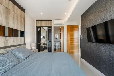 a bedroom with a large bed with a tv on a wall at C189 Beachside Luxury in Rawai Sea View and Gym in Rawai Beach