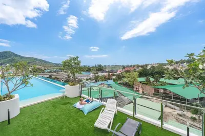a woman laying on a hammock on the balcony of a resort at C190 Sleek 1BR with Infinity Pool, Gym, Rooftop in Kamala Beach