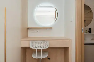 a bathroom with a vanity with a mirror and a chair at C190 Sleek 1BR with Infinity Pool, Gym, Rooftop in Kamala Beach