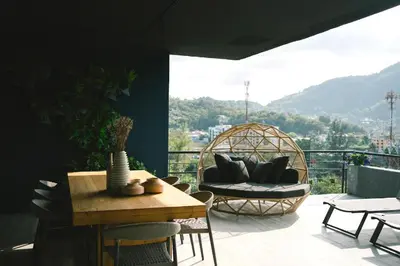 a balcony with a couch and a table and chairs at C191 CityGate Kamala Stylish Stay by Pools and Gym in Kamala Beach