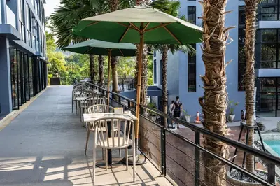 a row of tables and chairs with an umbrella at C191 CityGate Kamala Stylish Stay by Pools and Gym in Kamala Beach