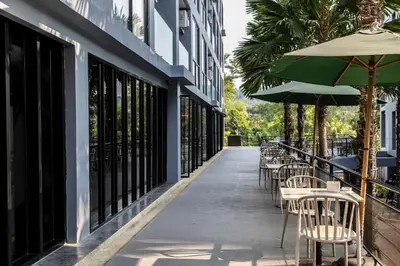 a row of tables and chairs with umbrellas on a sidewalk at C191 CityGate Kamala Stylish Stay by Pools and Gym in Kamala Beach