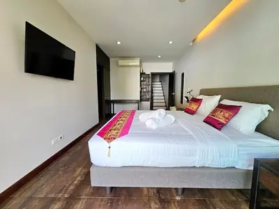 a bedroom with a large bed with a flat screen tv at 3-Bedroom Town House in Kamala in Kamala Beach