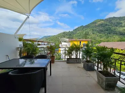 a balcony with a table and chairs and a mountain at 3-Bedroom Town House in Kamala in Kamala Beach