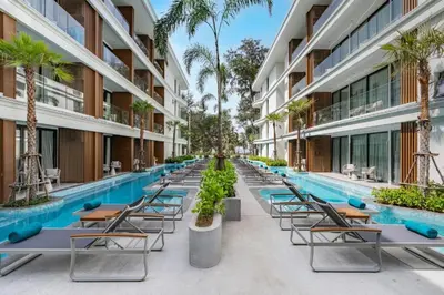 an empty pool at a hotel with chairs and palm trees at Sunshine Beach Residence Resort in Phuket Town