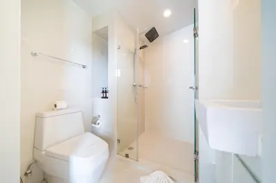 a white bathroom with a shower and a toilet at 1 Bedroom Apartment - The Aristo Resort by HCR in Surin Beach