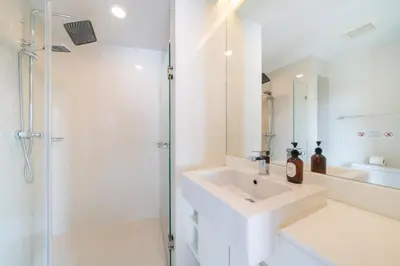 a white bathroom with a sink and a shower at 1 Bedroom Apartment - The Aristo Resort by HCR in Surin Beach