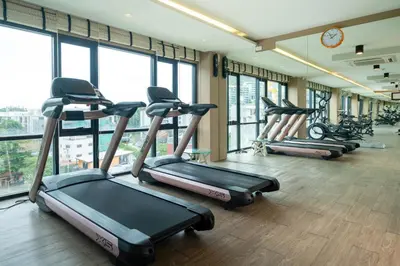 a gym with several treadmills in a room with windows at 1 Bedroom Apartment - The Aristo Resort by HCR in Surin Beach