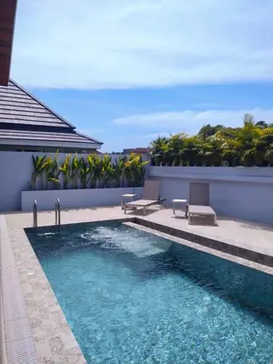 a swimming pool with two chairs next to a building at Rawai Villa in Rawai Beach