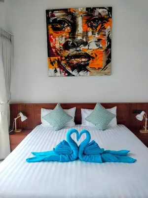 a bed with a blue bow on it with a painting at Rawai Villa in Rawai Beach