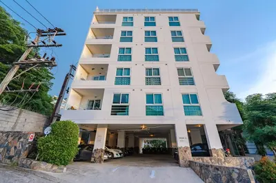 a tall white building with cars parked in front of it at C196 Condo 1BR Sea View & 5 Min to Beach in Kata Beach