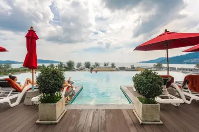 a pool at a resort with people sitting in chairs and umbrellas at C197 Condo 1BR with Pool 3 Min Walk to Beach in Patong Beach