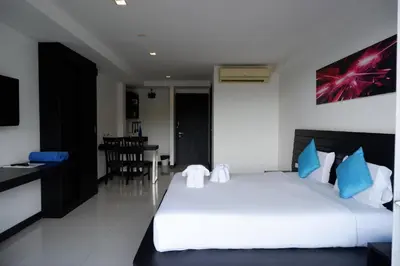 a bedroom with a white bed and a dining room at Lae Lay Suite in Karon Beach