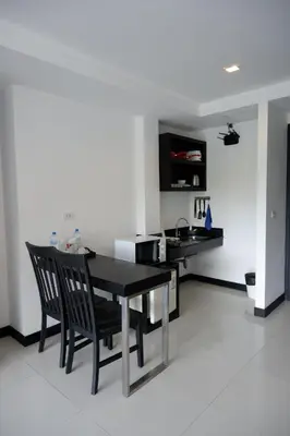 a dining room with a black table and chairs at Lae Lay Suite in Karon Beach