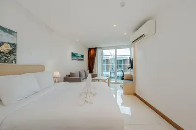 a bedroom with a large white bed and a living room at C198 Oceanview Stay Gym, Pool & Walk to Beach in Rawai Beach