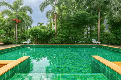 a swimming pool with two chairs and palm trees at C199 Condo 1BR Walk to Lake, Beach, Bars & Market in Rawai Beach