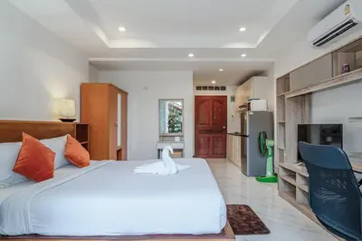 a bedroom with a large white bed and a kitchen at C199 Condo 1BR Walk to Lake, Beach, Bars & Market in Rawai Beach