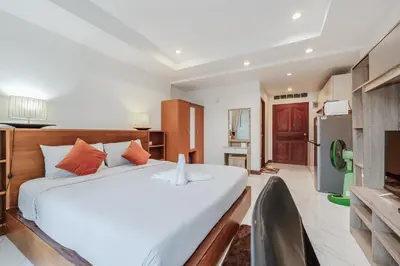 a bedroom with a large white bed and a kitchen at C199 Condo 1BR Walk to Lake, Beach, Bars & Market in Rawai Beach